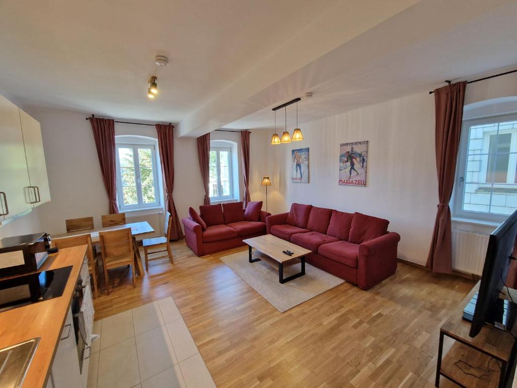 a living room with red couches and a table at Mariazell Appartement Kugeltreff in Mariazell
