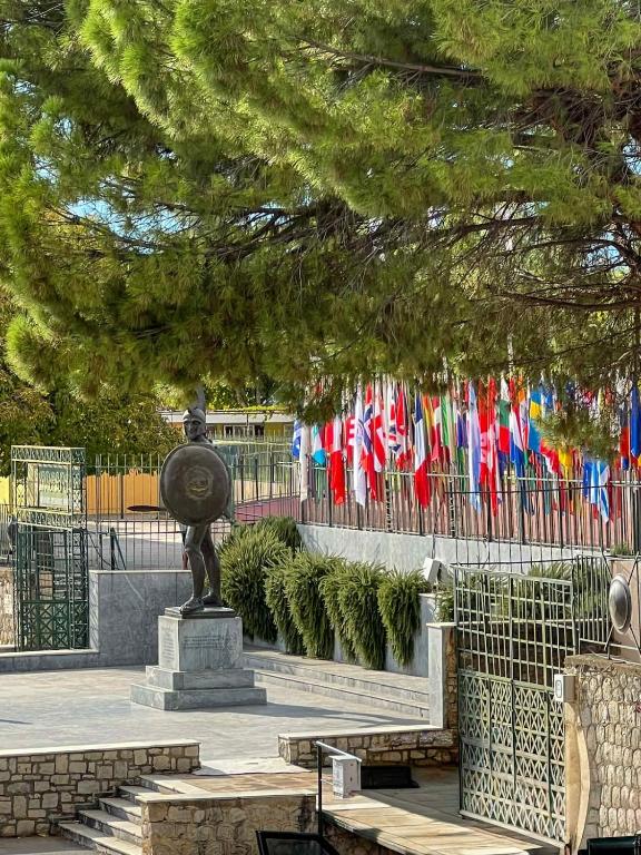a statue in front of a fence with flags at Vintage house overlooking the statue of Leonidas in Sparti