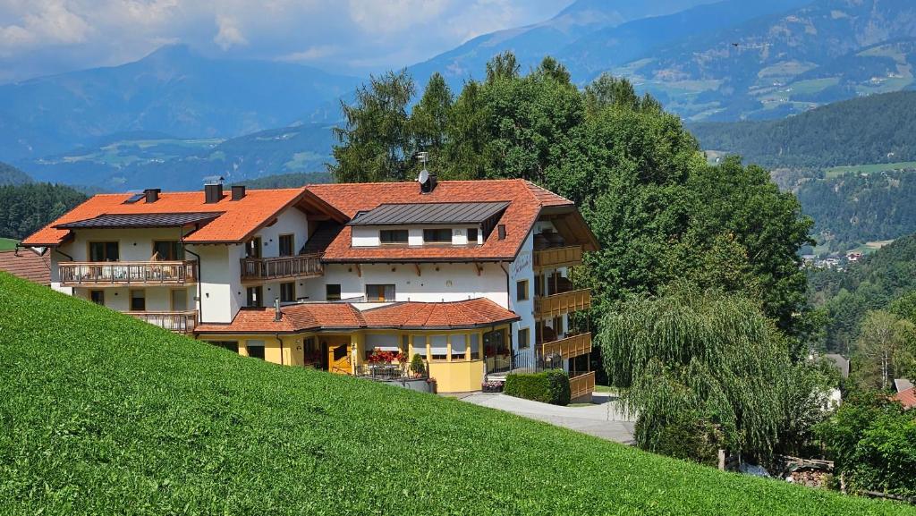a large house on top of a green hill at Apartment Pichlerhof in San Lorenzo di Sebato