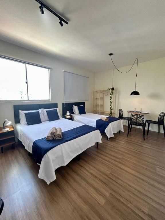 two beds in a large room with wooden floors at Ap Smart Hub Agro in Piracicaba