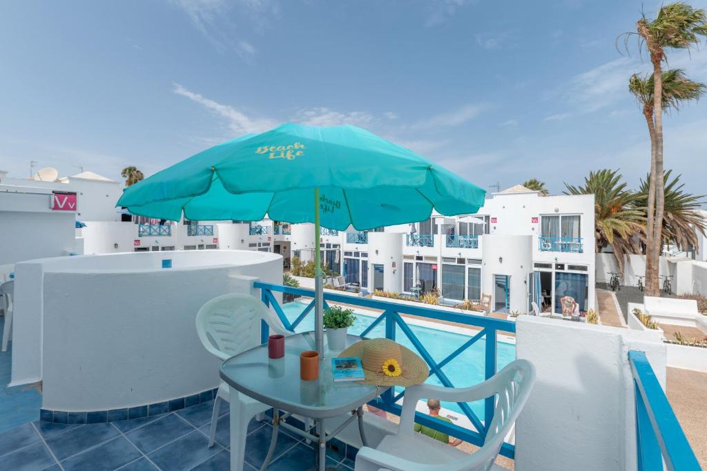 einen Tisch und Stühle mit Sonnenschirm auf dem Balkon in der Unterkunft Vv Sueño Del Mar, Puerto del Carmen in Puerto del Carmen