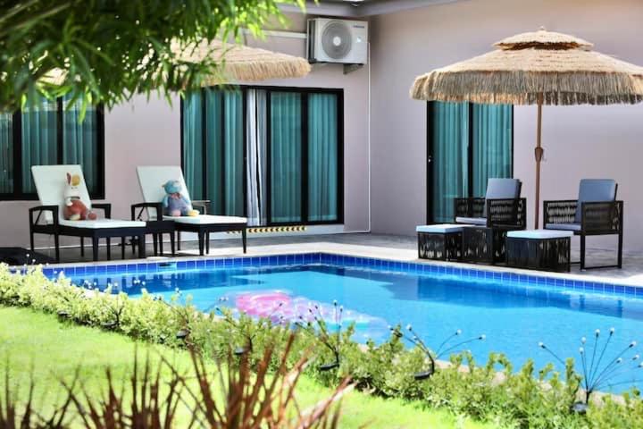 a swimming pool with chairs and an umbrella at 派对家园-11卧室独栋大泳池私密别墅 in Ban Huai Yai