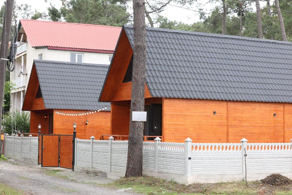 ein Haus mit einem Zaun davor in der Unterkunft Cottage in Forest Wave - კოტეჯი ტყის ტალღებში in Grigoleti