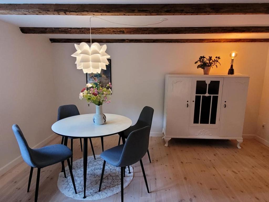 - une salle à manger avec une table, des chaises et un vase fleuri dans l'établissement Villa Fuga kælderlejlighed, à Jelling