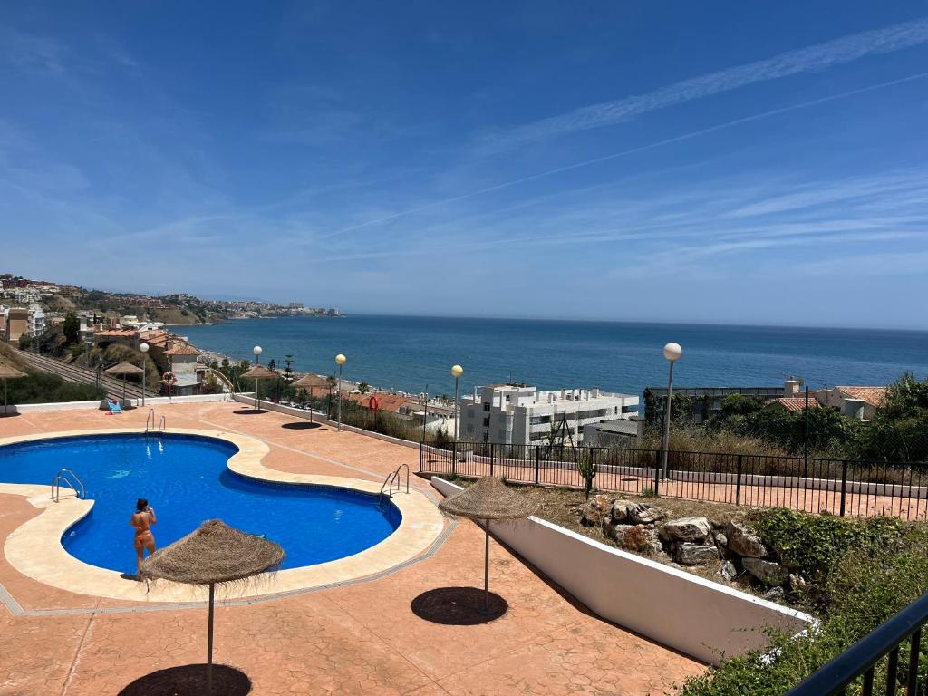 a woman standing next to a swimming pool next to the ocean at Carvajal casa Tucan in Fuengirola