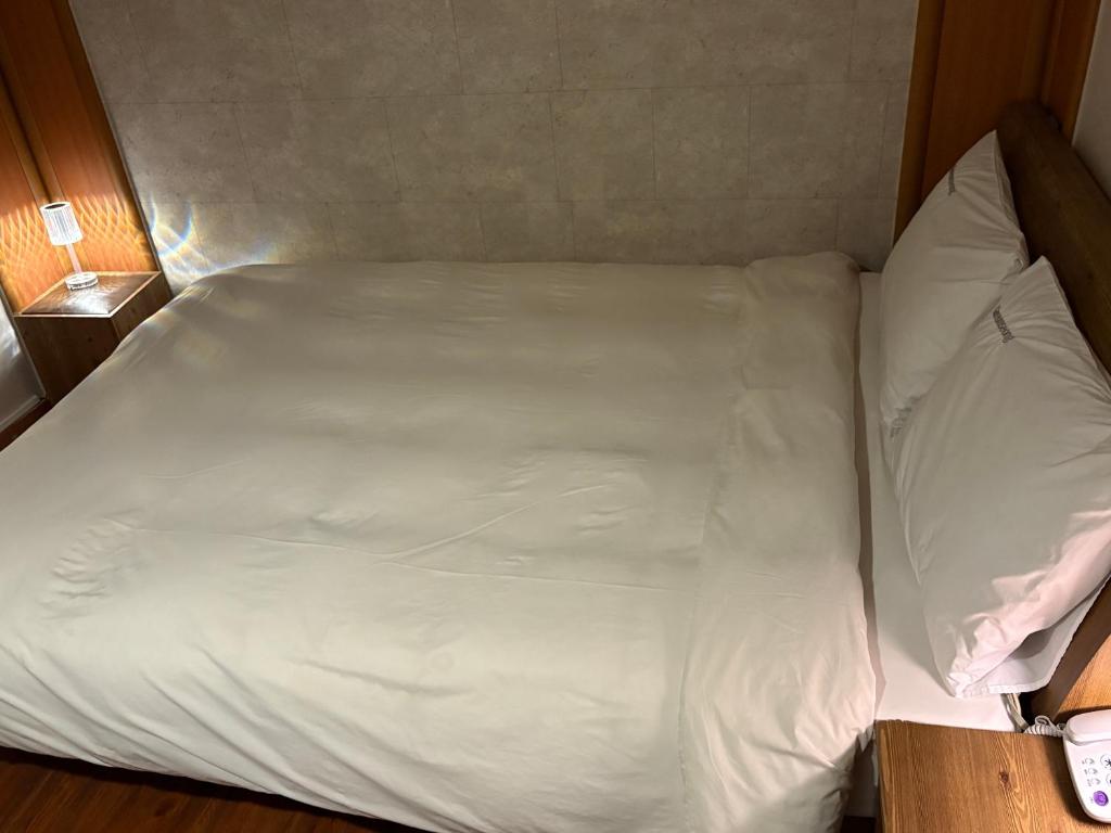 ソウルにあるGooreumseong motelの部屋にある白いシーツと枕が置かれたベッド