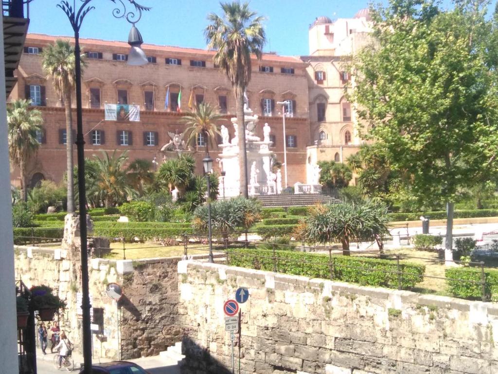 a building with a fountain and palm trees in front of it at Casa Normanna in Palermo