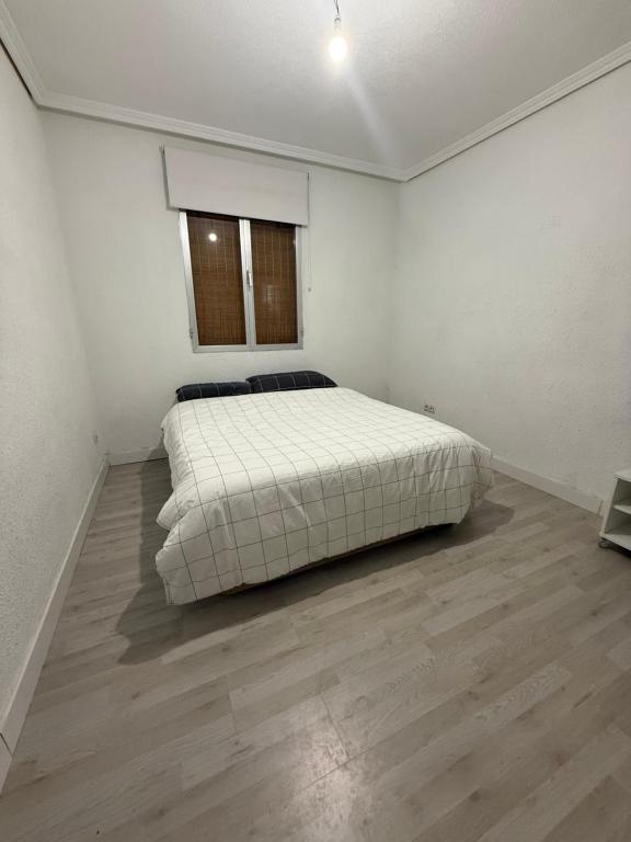 Un dormitorio con una cama en una habitación blanca. en Petithouse Madrid Camino Viejo, en Madrid