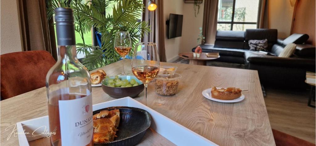 a bottle of wine and a plate of food on a table at Lakefront Cottage Gelderland BBQ & tuin 6pers in Ewijk