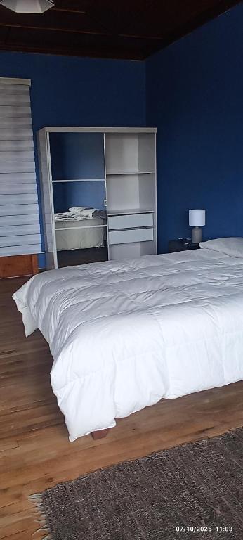 a bedroom with a white bed with a blue wall at Mdrag in Punta Arenas