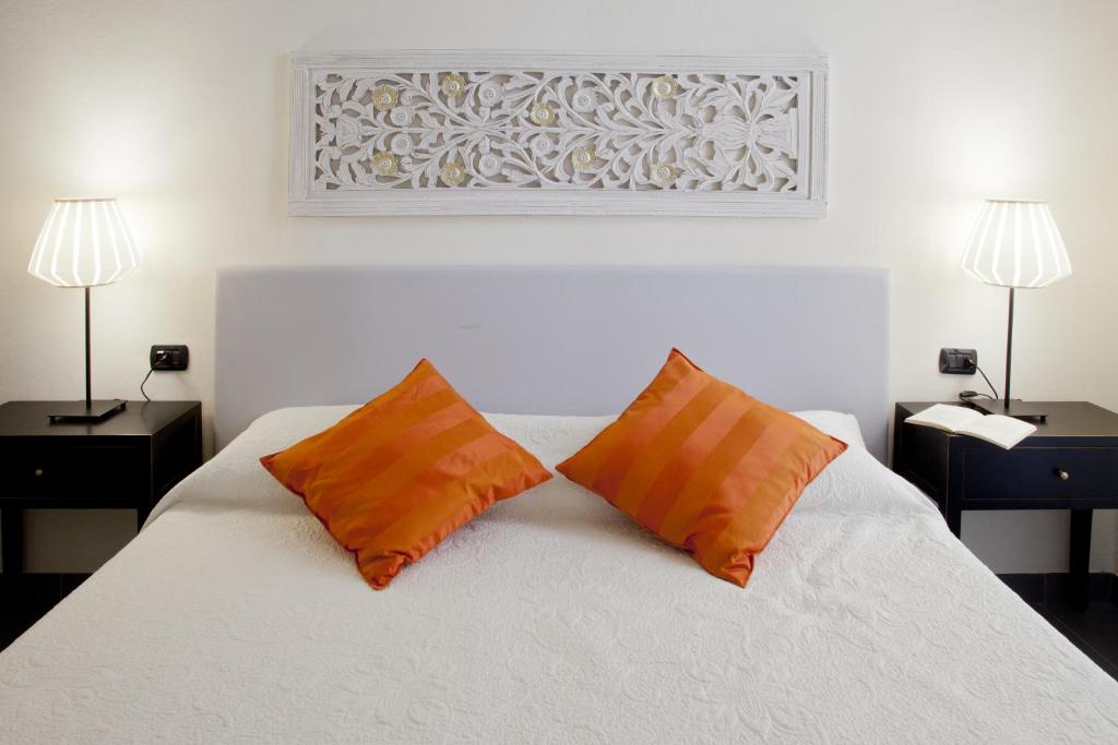 a bedroom with a white bed with two orange pillows at Canto dei Mille in Florence