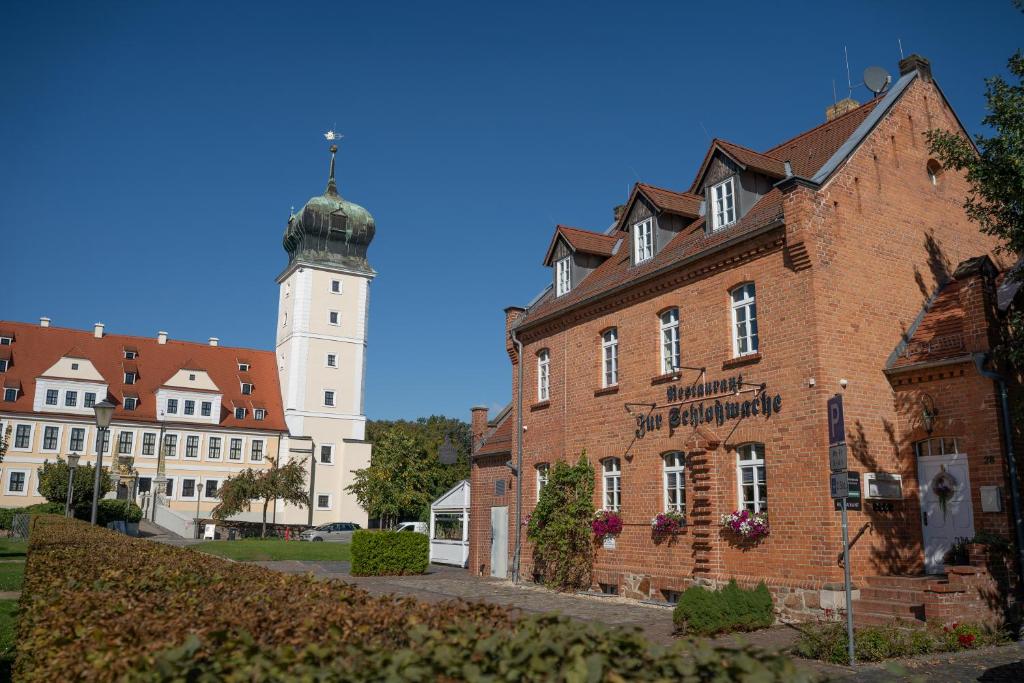 a large brick building with a clock tower in the background at Appartments Zur Schlosswache Delitzsch in Delitzsch