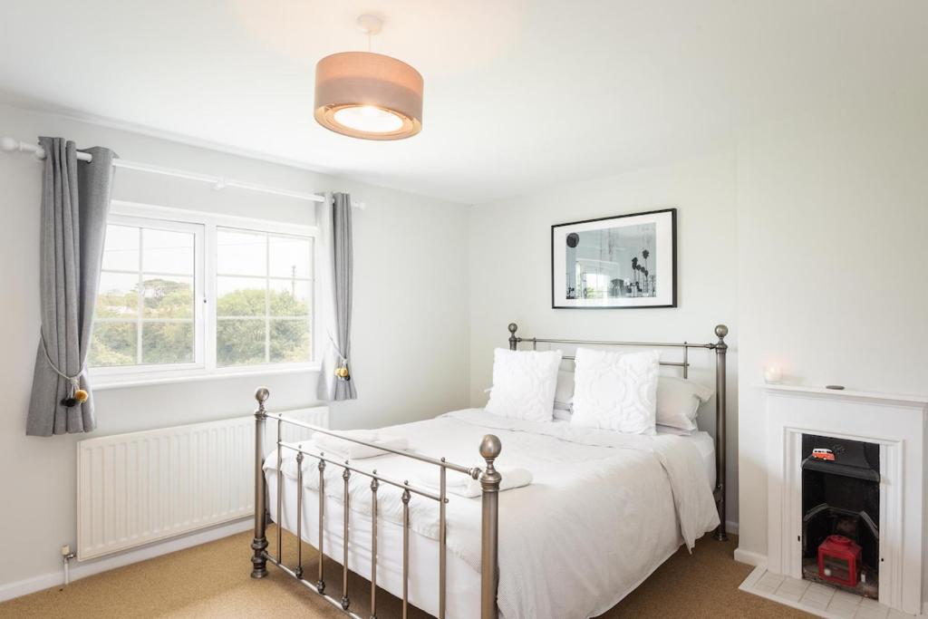 a white bedroom with a bed and a fireplace at Spacious 3 Bed Cottage Near Beaches in Georgeham