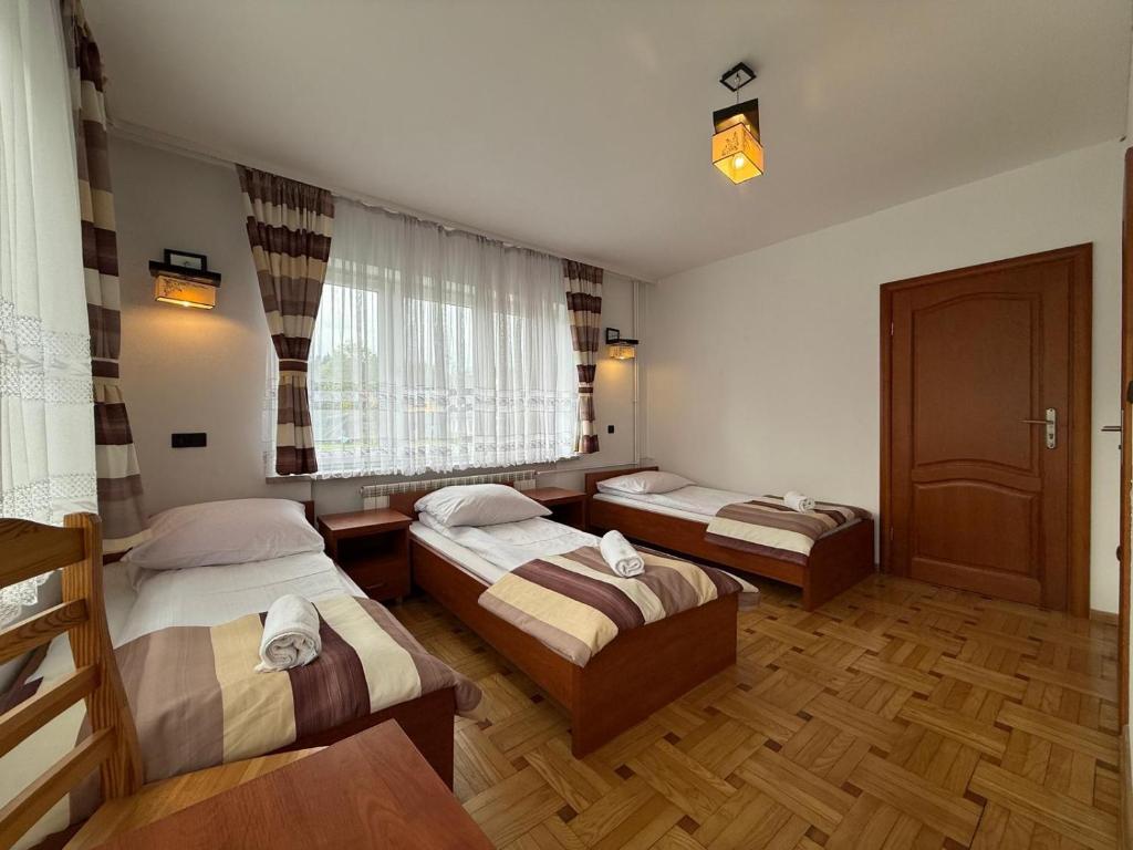a bedroom with three beds and a window at Pokoje W Górach Savanna in Biały Dunajec