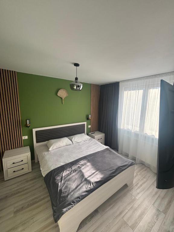 a bedroom with a bed and a green wall at Central Elegant Lofts in Piatra Neamţ