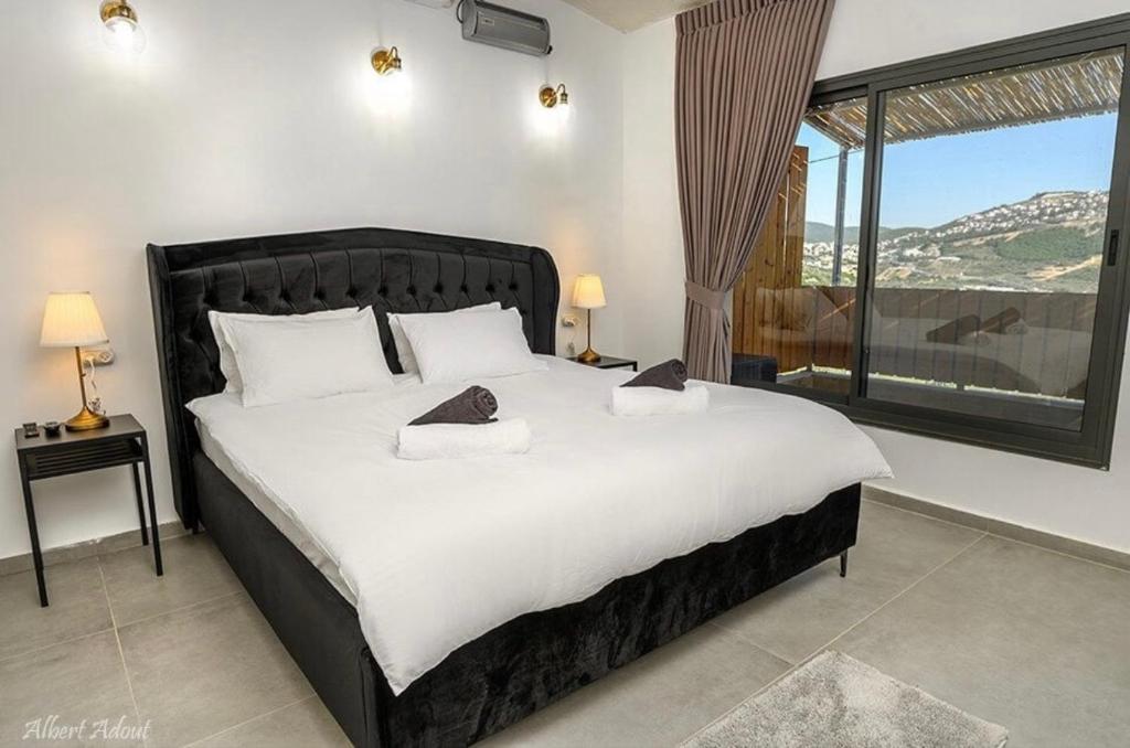 a bedroom with a large bed and a large window at וילה סאן טורינו - Vila San Torino in Elqosh