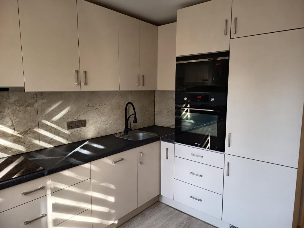 eine Küche mit weißen Schränken und einer schwarzen Arbeitsplatte in der Unterkunft Vieno kambario butas Šiauliuose in Šiauliai