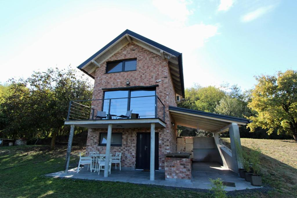 een stenen huis met een balkon en een terras bij Kuća za odmor MIRINA in Aljmaš