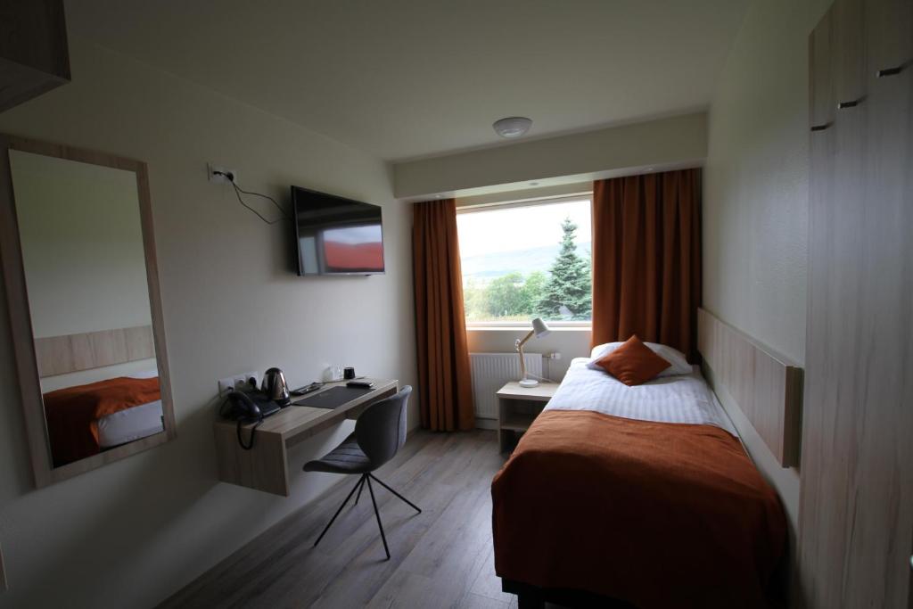a hotel room with a bed and a sink and a window at Hotel Hallormsstadur in Hallormsstaður