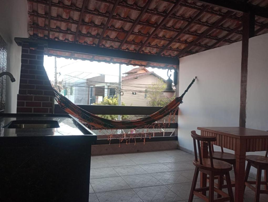 a hammock in a room with a table and a window at Varanda palmeiras in Cabo Frio