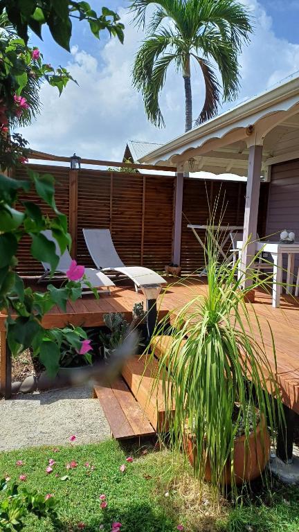a patio with a bench and a table and a palm tree at TI-MANGO 1km de la plage communale quartier résidentiel in Sainte-Anne