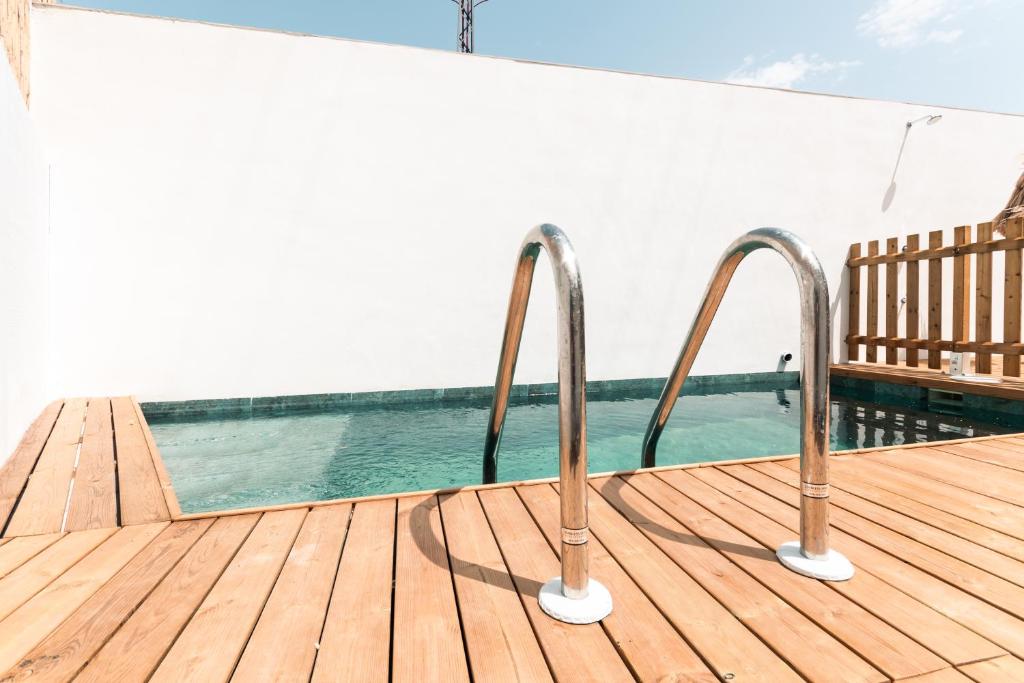 a wooden deck with a pool and two metal rails at Villa sunset piscina privada in Luque