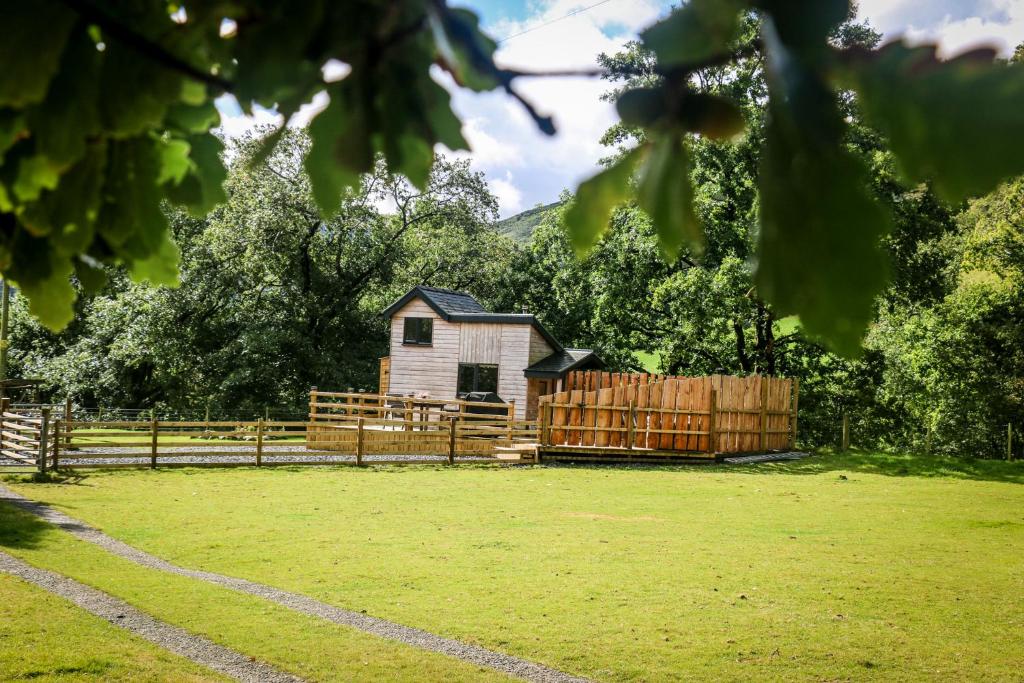 a house in a field with a fence at Ty Nant Cafn in Machynlleth
