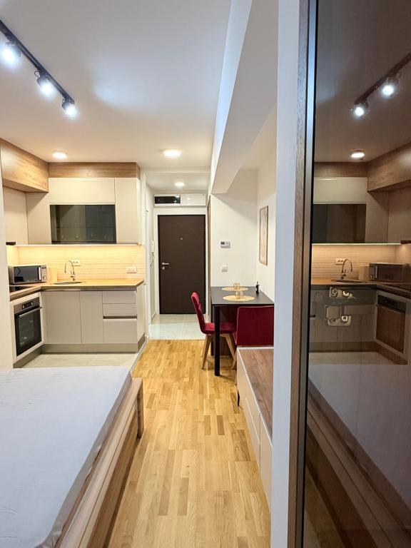 una cocina con armarios blancos y una mesa con una silla roja en Apartment UNA, en Pančevo