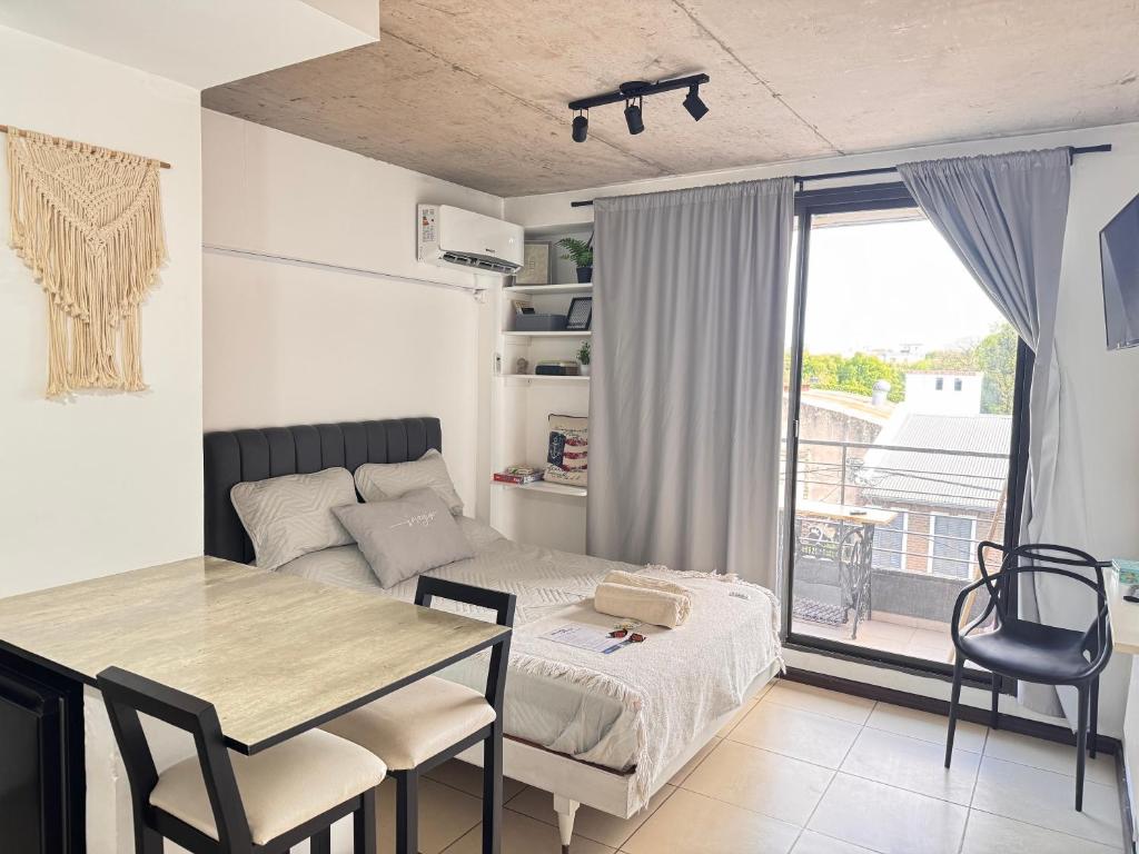 ein Zimmer mit einem Bett und einem Tisch und einem Fenster in der Unterkunft Montevideo Suites con Balcón in Rosario