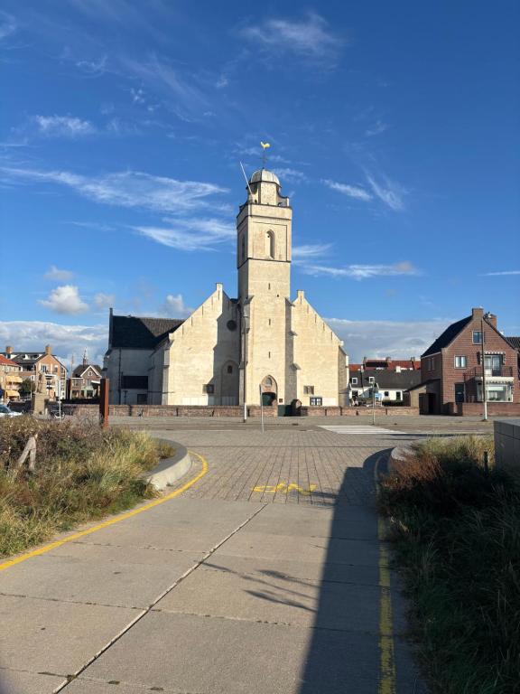 a large white building with a clock tower on a street at Duin 10 in Katwijk aan Zee