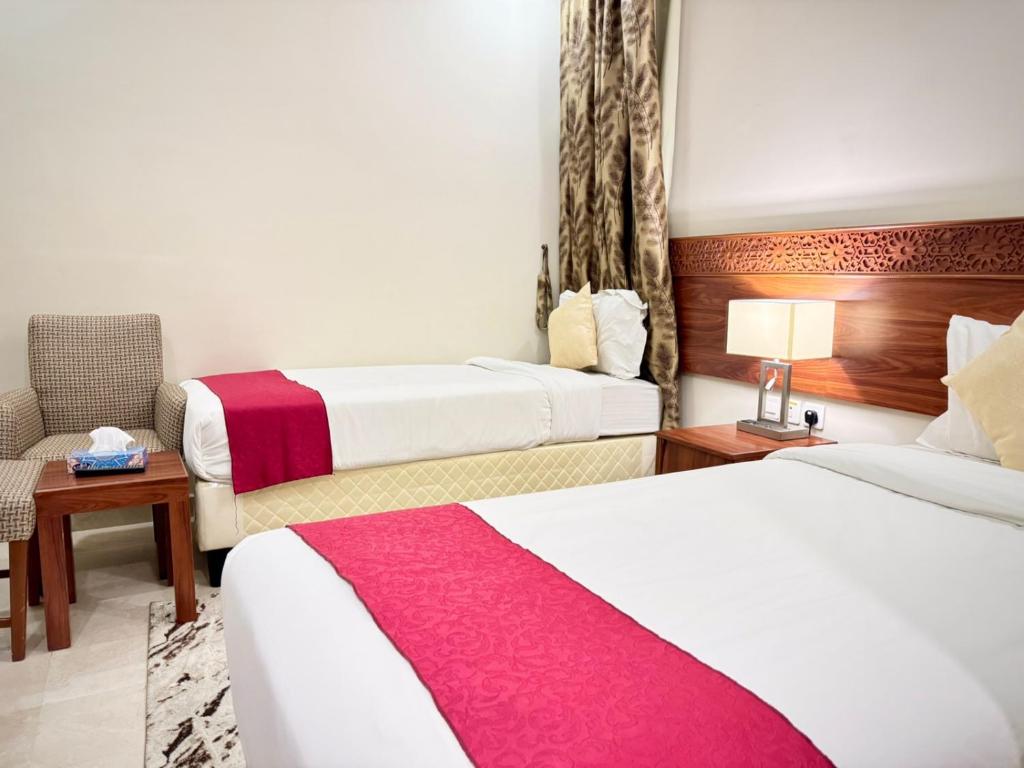 a hotel room with two beds and a chair at فندق رفاهية العزيزية in Al ‘Azīzīyah