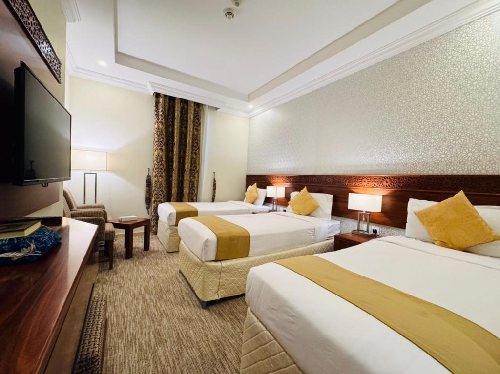 a hotel room with two beds and a flat screen tv at فندق رفاهية العزيزية in Al ‘Azīzīyah