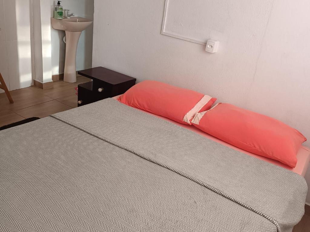 a bed with a red pillow on top of it at Kitnet Rústica Blumenau in Blumenau