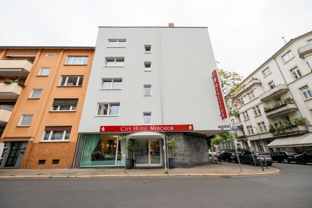 un edificio blanco con una señal roja delante de él en City Hotel Mercator, en Frankfurt
