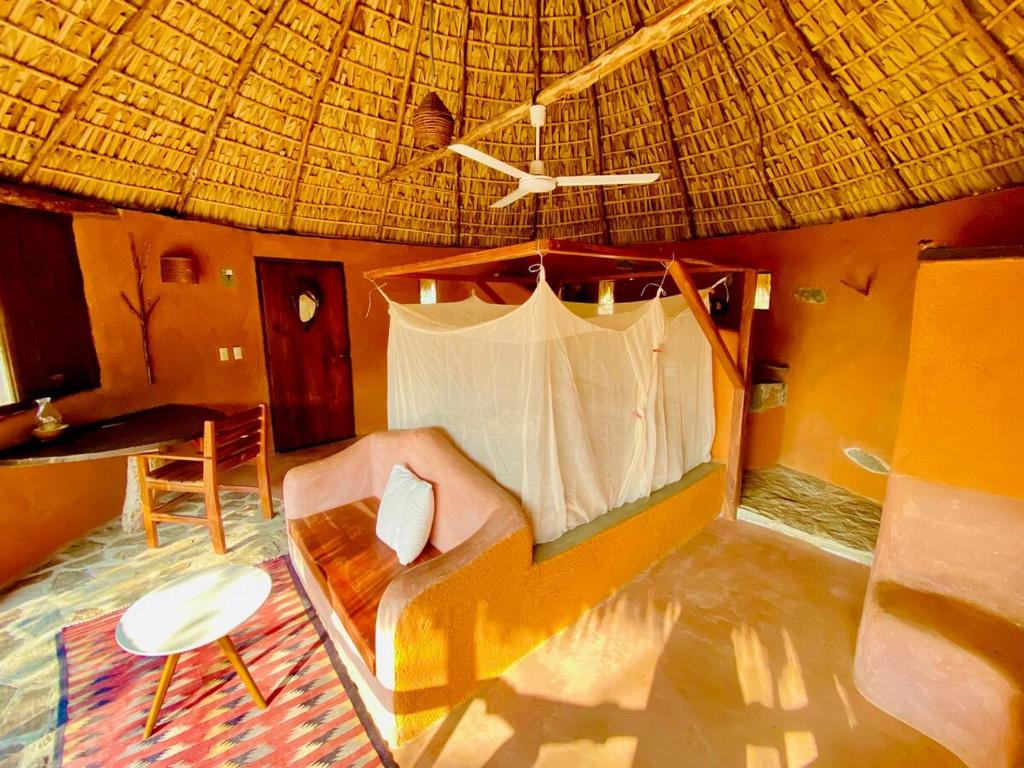 a living room with a couch and a straw roof at Flor de Arena in Arroyo Cruz