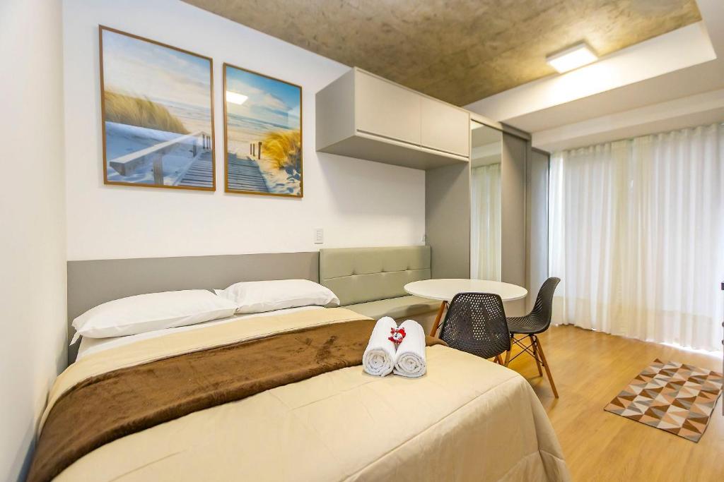 a hotel room with two beds and a table at Studio Completíssimo Próximo a PUC PR - URB0403 in Curitiba