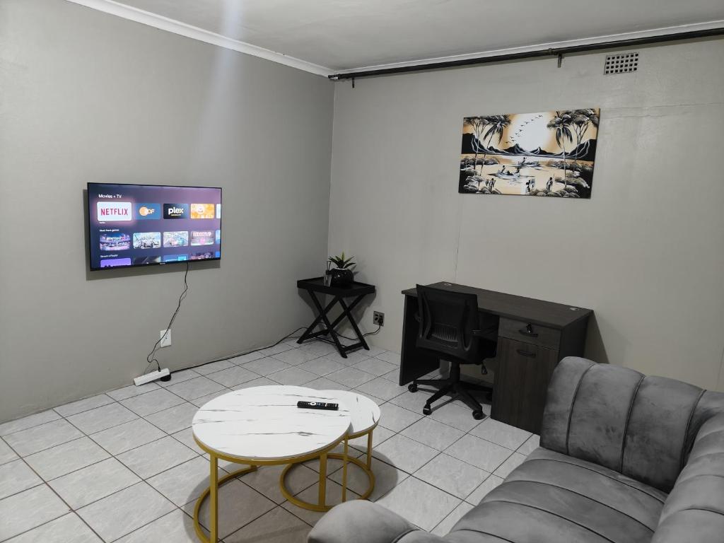 a living room with a couch and a table and a tv at Tranquil Leisure in Midrand