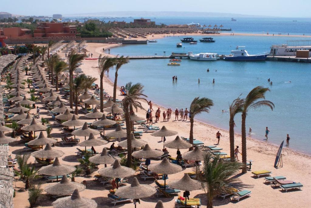 a beach with a bunch of umbrellas and palm trees at Giftun Azur Resort in Hurghada