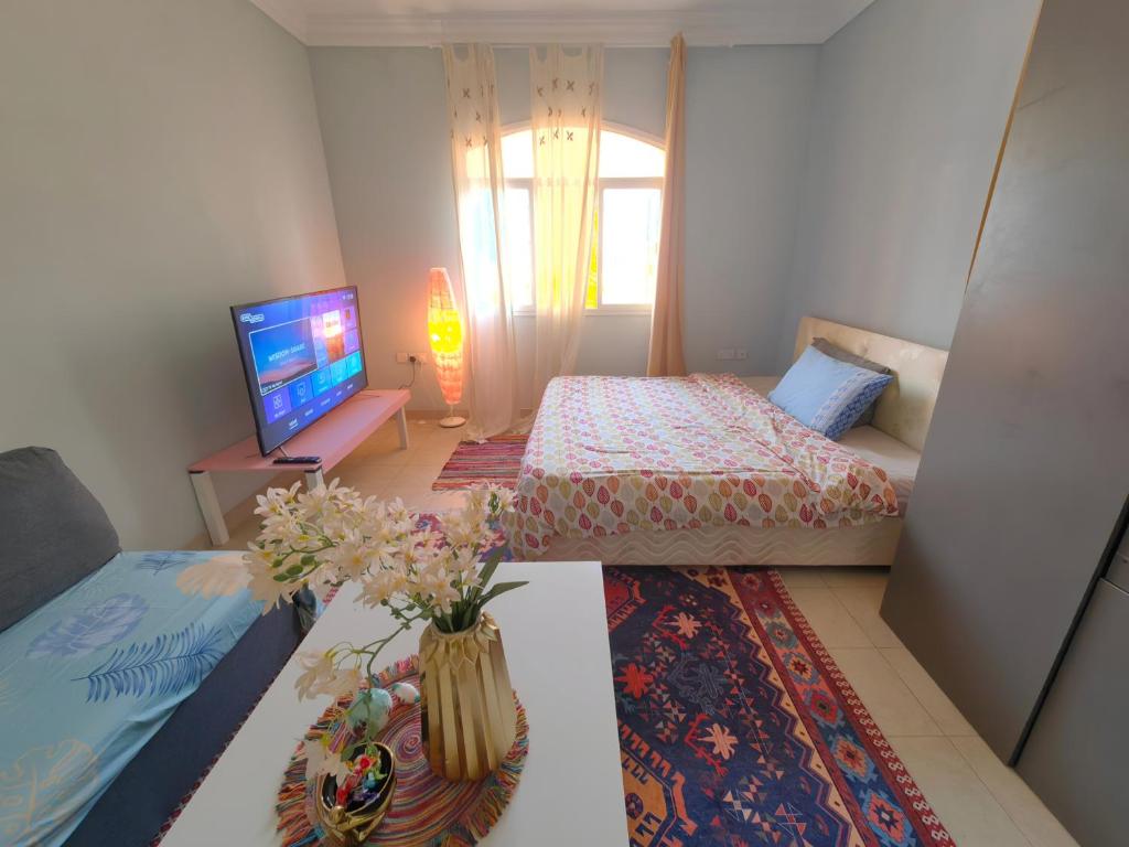 1 dormitorio con 2 camas y un jarrón con flores sobre una mesa en bloom Room, en Mascate