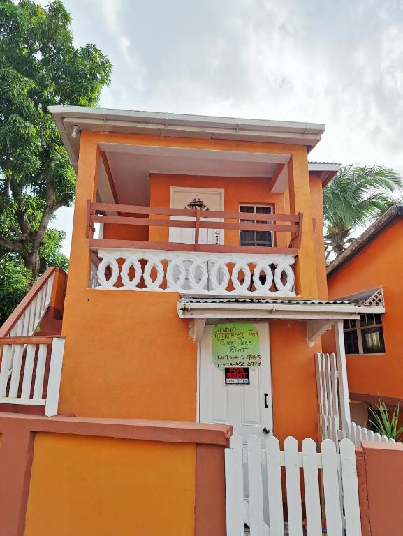 a orange house with a white fence at EMME Escape in Saint Georgeʼs
