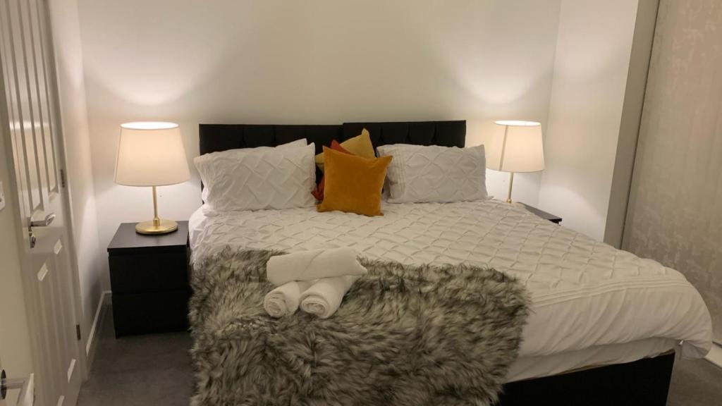 a bedroom with a large bed with two lamps at Fabulous 3 bed house close to Lakeside shopping Centre in West Thurrock