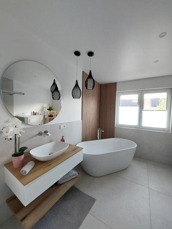 a bathroom with a tub and a sink and a mirror at Ferienwohnung Senfnest in Ober-Ramstadt