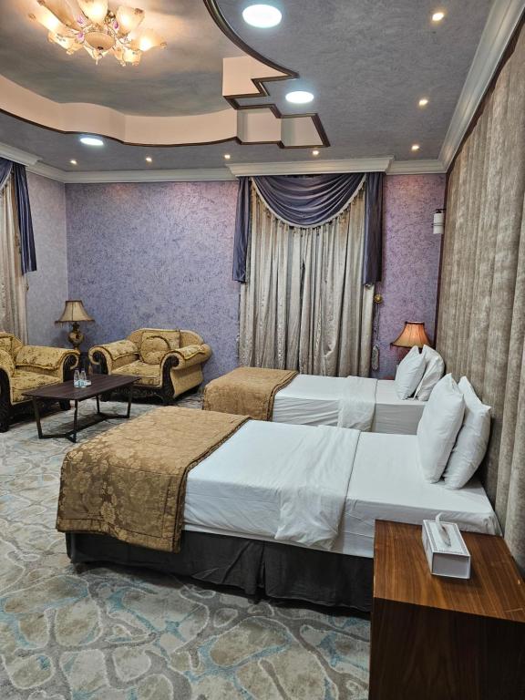 a hotel room with two beds and a couch at اجنحة العلا الفندقية للضيافة الخاصة AlUla Hotel Suites for Special Hospitality in AlUla