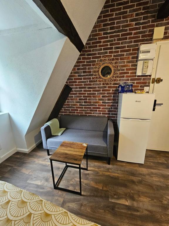 a couch and a table in a room with a brick wall at Jolie studio en cetre ville de Montluçon 20 min à pieds de la gare in Montluçon