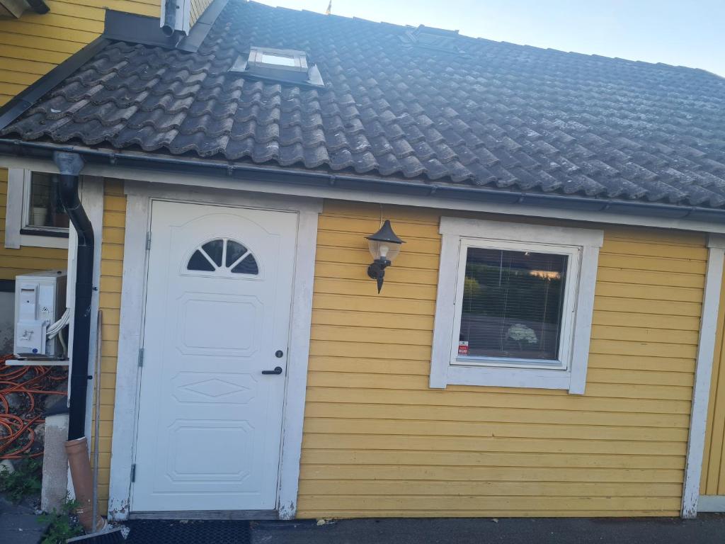 una pequeña casa con una puerta blanca y una ventana en Home near both town and nature, en Norrköping