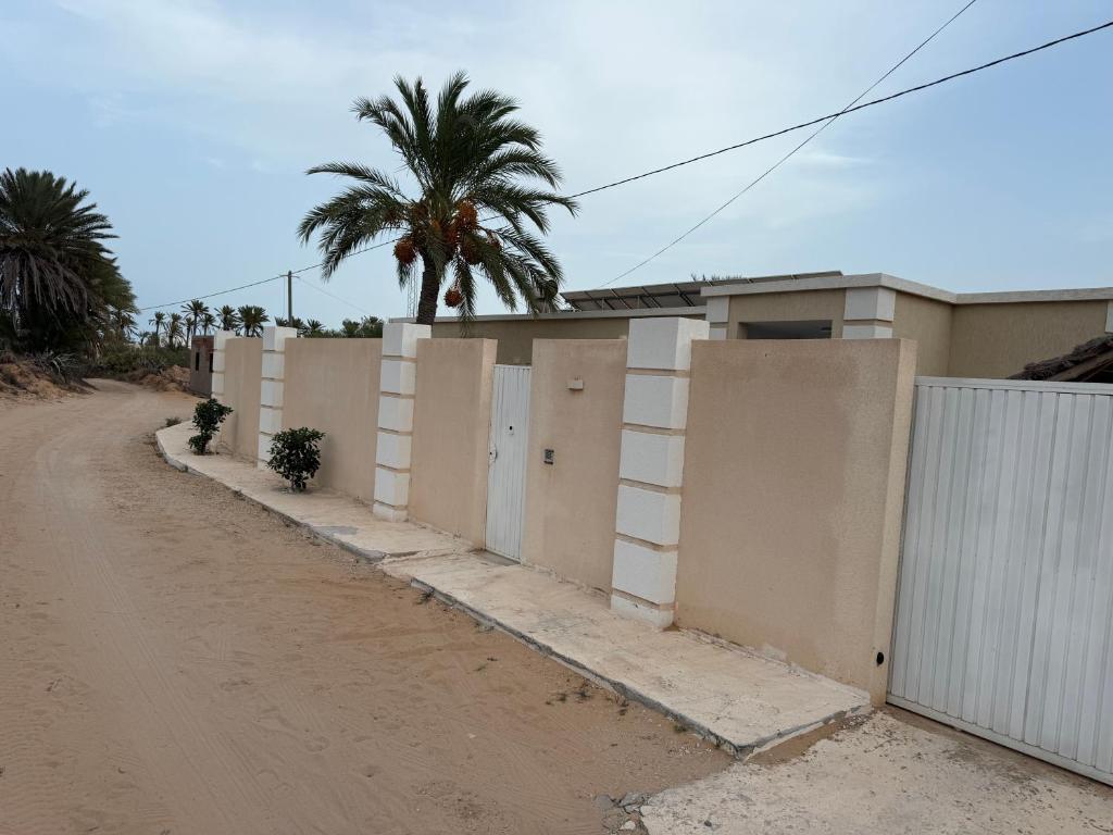 a dirt road with a fence and a palm tree at Villa Maghrebi in Al Ḩaddādah