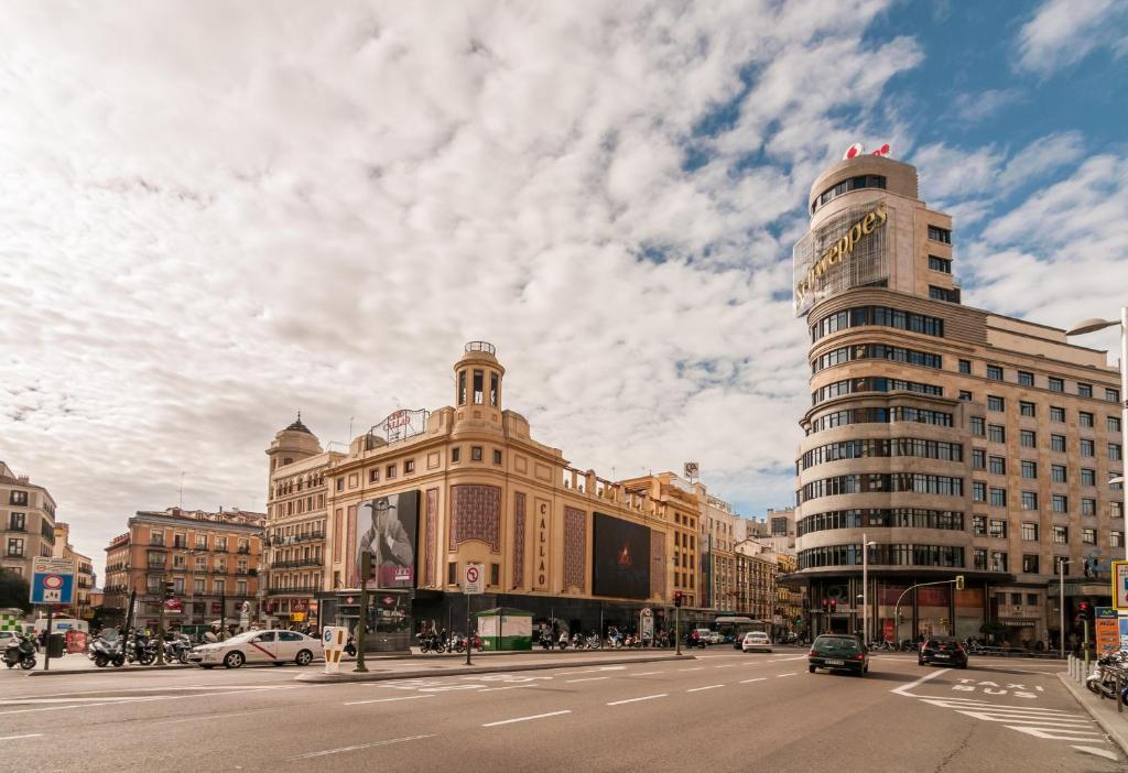 马德里Apartment Sol Gran Vía的阴天的繁忙城市街道,有建筑