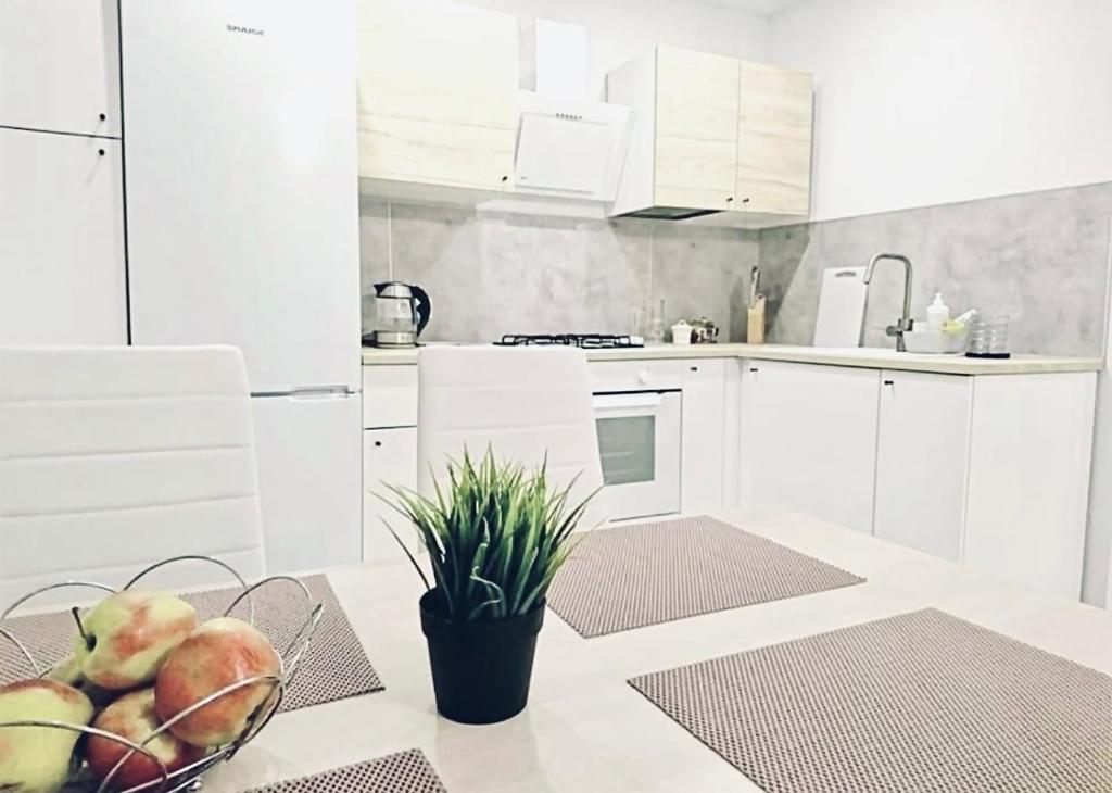 una cocina con armarios blancos y un bol de fruta en M&M Apartment I near Panevezys, en Velžys