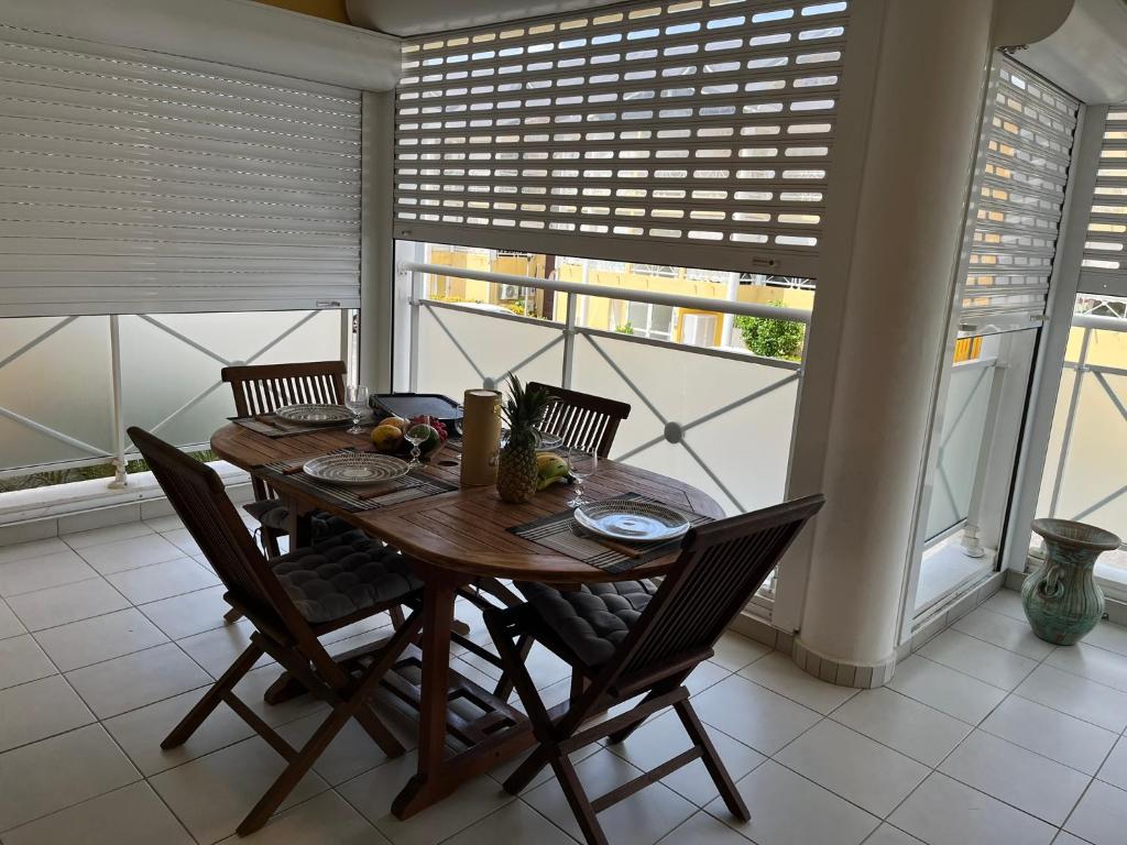 a wooden table and chairs in a room with windows at Fleur de Paradis in Saint-François