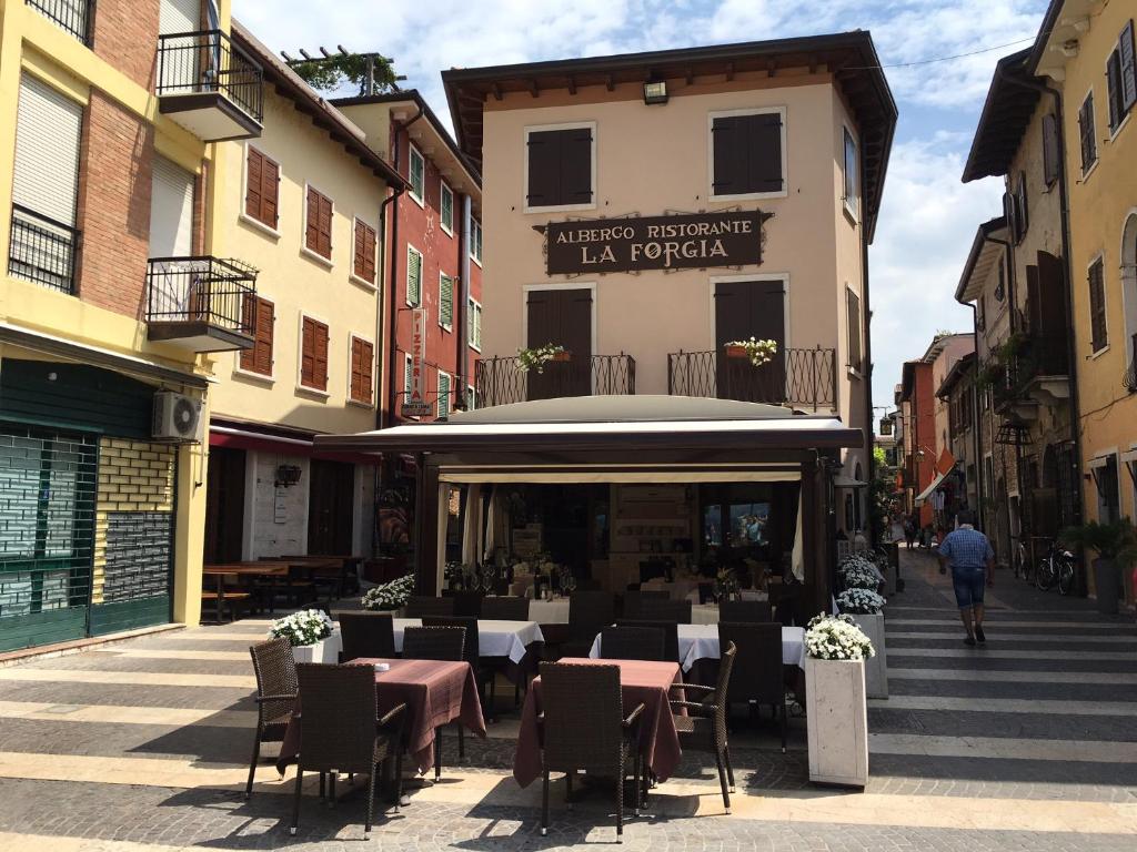 ein Restaurant mit Tischen und Stühlen auf einer Straße in der Unterkunft Camere La Forgia in Lazise